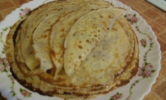 Efter 15 minuter, börja baka pannkakor. Bakprocessen är densamma som för vanliga pannkakor. Smörj formen med olja strax före den första pannkakan. Lägg de bakade tunna pannkakorna med gräddfil med hål på en tallrik, smörj varje pannkaka med smör, och du kan servera. Smaklig måltid!