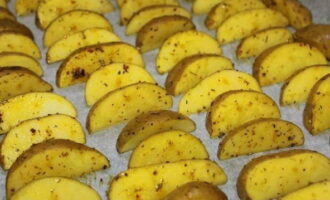 Acoperiți o foaie de copt cu pergament. Pune pe ea felii de cartofi pregătite. Punem aluatul la cuptorul preincalzit la 180 de grade pentru 20-25 de minute. 