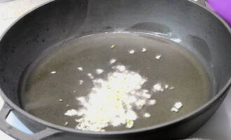 A continuació, prepareu la salsa de pollastre. Picar els grans d'all pelats amb un ganivet i fregir-los una mica en una altra paella amb oli ben calent.