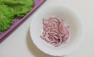 Gupitin ang peeled salad na sibuyas sa manipis na kalahating singsing, ihalo ang mga ito sa suka ng alak at iwanan upang mag-marinate. Banlawan ang mga dahon ng lettuce na may malamig na tubig at tuyo gamit ang isang napkin.