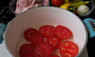 Ta en behållare med tjocka väggar och en tung botten. Skölj de köttiga tomaterna, torka dem och skär dem i ganska tjocka skivor. Fodra botten av behållaren med dem.