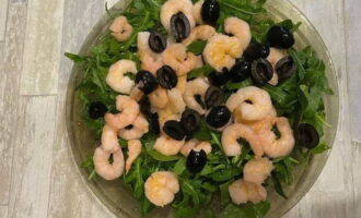 Talleu les olives sense pinyol al llarg i repartiu-les per sobre de les gambes.