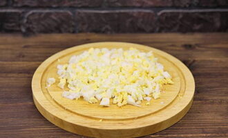 Pakuluan ang mga itlog, palamig, alisan ng balat at i-chop ng pino.