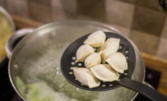 Voeg met een schuimspaan de dumplings geleidelijk toe aan de pan.