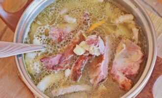 Voeg varkensribbetjes toe en bedek met water. Pel het teentje knoflook, plet het met een mes zodat alle smaak vrijkomt en voeg het toe aan de bouillon. Breng aan de kook, zet het vuur laag, kook afgedekt gedurende 40-50 minuten.