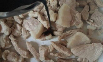 Đặt các miếng thịt lợn vào chảo rán. Thêm nước tương và đường.