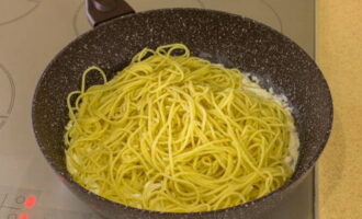 Breng de spaghetti over naar de pan met zeevruchten.