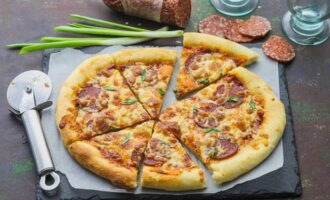 Traieu la pizza calenta del forn amb cura per no cremar-vos. Transferiu amb cura a un plat de servir. Talleu en porcions amb un ganivet especial. Serveix i tracta els teus amics. Bona gana!