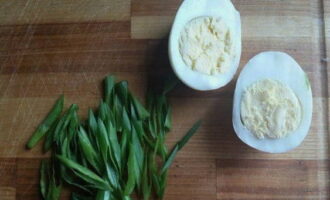 Luộc trứng gà, để nguội, bóc vỏ và chia làm đôi. Chuẩn bị miếng hành lá.