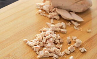 Cắt phi lê gà đã luộc sẵn và để nguội thành những khối nhỏ.