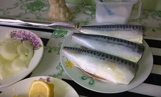 Loại bỏ đầu, đuôi, nội tạng và đặc biệt là lớp màng đen trên thân thịt bằng cách cắt bụng theo chiều dọc. Sau đó rửa sạch cá dưới vòi nước chảy. Gọt vỏ và cắt hành tây thành nửa vòng. Rửa sạch chanh và cắt vỏ thành những lát mỏng.