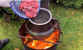 Plaats de Afghaanse ketel boven een open vuur/vreugdevuur en verwarm de plantaardige olie erin. Bak vervolgens de stukken lamsvlees goed in olie tot ze aan alle kanten goudbruin zijn. Bak het vlees minimaal 10 minuten.