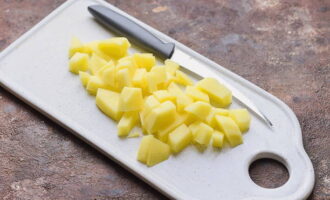 Balatan ang mga patatas, banlawan at gupitin sa maliliit na cubes, ilagay sa isang kasirola na may nilutong mga gisantes at lutuin ng isa pang 20 minuto.