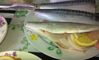 Rắc cá thu đã chuẩn bị bên ngoài và bên trong với muối và gia vị. Đặt hành tây xắt nhỏ với lát chanh vào bụng cá thu.