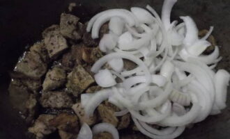 Ara heu de preparar les verdures per posar-les en capes en un calder. Netegeu-los i esbandiu-los. Talleu la ceba a mitges rondelles i poseu-la a sobre de la carn de porc fregida.