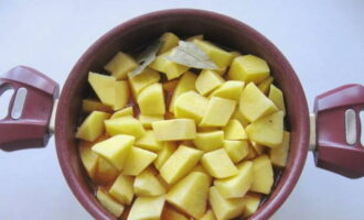 Medan kycklingen kokar, skala och skölj potatisen. Skär den i medelstora bitar av godtycklig form. Lägg potatisskivorna ovanpå de stuvade klubborna, tillsätt salt, tillsätt ett lagerblad och tillsätt lite vatten.