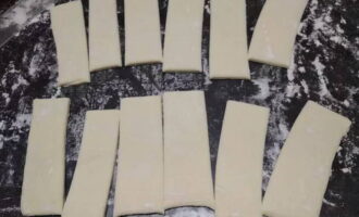 Abans de començar a cuinar, traieu el paquet de massa del congelador i deixeu-lo a temperatura ambient durant mitja hora. A continuació, empolseu la superfície de treball amb una petita quantitat de farina i talleu la capa en rectangles.