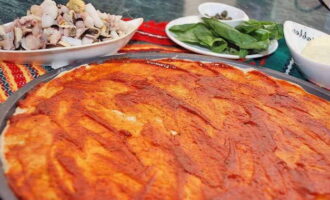 Ungeți baza de pizza cu sos de roșii.
