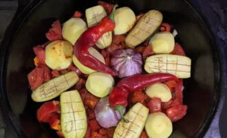 Ta bort det övre skalet från vitlökshuvudena. Stick ner huvudena i grönsakerna. Skala, tvätta och fördela potatisen hel i en kittel. Skär auberginema på längden och lägg dem mellan potatisen. Tillsätt en hel het peppar. Glöm inte att salta den.