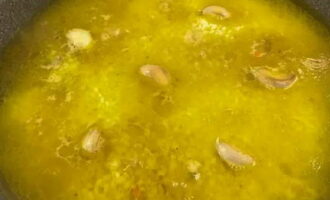 Spoel de rijst af tot het water helder is en voeg toe aan de aromatische zirvak. Maak het waterpas. Dompel gepelde knoflookteentjes onder in rijst. Giet kokend water tot de rijst 1,5 centimeter onder staat.