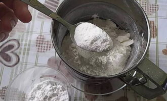 Giet tarwebloem, bakpoeder en aardappelzetmeel in een zeefbeker.