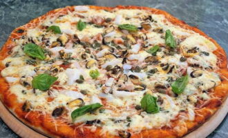 Pizza apetisantă cu fructe de mare acasă este gata. Tăiați și serviți!