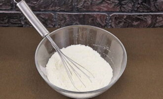 We beginnen met koken door het deeg te bereiden. Om dit te doen, moeten we gezeefde bloem, zout, kristalsuiker en instantgist in een diep bord combineren.Meng alle droge ingrediënten grondig.