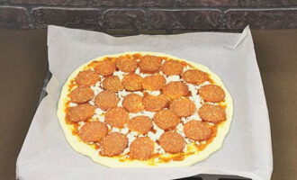 We snijden de worst in dunne plakjes en rangschikken deze symmetrisch langs de gehele diameter van het werkstuk. Plaats in een voorverwarmde oven op 200°C en bak ongeveer 15-20 minuten, afhankelijk van het vermogen.