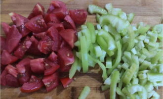 A paradicsomot durvára vágjuk, a kaliforniai paprika héját pedig szeletekre vágjuk.