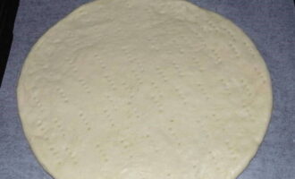 Estireu la massa de pizza fina en un cercle i col·loqueu-la sobre una safata de forn folrada amb paper pergamí. Fem punxades per tota la superfície amb una forquilla o un escuradents.