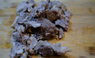 Scoateți carnea fiartă din tigaie și împărțiți-o în bucăți mici. Se strecoară bulionul printr-o sită cu găuri fine.