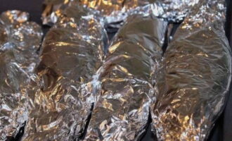 Balutin nang mahigpit ang bawat isda ng foil. Ilagay ang mga paghahanda sa isang baking sheet.
