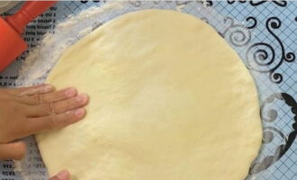 Gamitin ang iyong mga kamay upang pantayin ang kuwarta at pagpuno, dagdagan ang diameter. Pagkatapos ay dumaan kami sa isang rolling pin hanggang sa ang kapal ng semi-tapos na produkto ay 2-3 sentimetro. Gamitin ang iyong mga kamay upang pantayin ang kuwarta at pagpuno, dagdagan ang diameter. Pagkatapos ay dumaan kami sa isang rolling pin hanggang sa ang kapal ng semi-tapos na produkto ay 2-3 sentimetro.