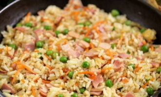 Doe nu de rijst in de pan, voeg sojasaus, zout en peper toe - meng en verwarm de ingrediënten gedurende minimaal drie minuten.
