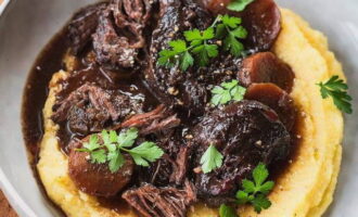 Haal de gekookte wangen uit de saus. Zeef de saus. Doe de aardappelpuree in een serveerschaal. Giet de saus erover en leg de wangen erop. Mals vlees valt uiteen in vezels. Garneer met je favoriete groen en serveer aan je dierbaren. Genieten!