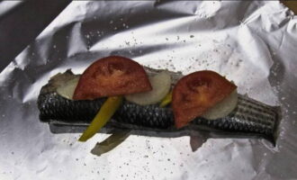 Lägg skivor av grönsaker på fisken och salt om så önskas.