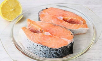 Nấu cá hồi trong chảo rất nhanh chóng và dễ dàng. Hãy chuẩn bị hai miếng cá hồi nướng.Chúng tôi rửa chúng và lau khô bằng khăn giấy. Đặt vào một cái bát thuận tiện và đổ nước chanh.