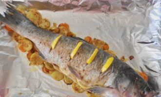 Đặt cá chép bạc ngâm chua lên trên và đặt những lát chanh vào vết cắt.