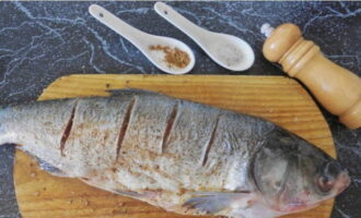 Chúng tôi thực hiện một số vết cắt nông xiên và chà xát cá chép bạc lên tất cả các mặt với gia vị và muối, rắc nước ép trái cây họ cam quýt và để ngâm trong 20 phút.