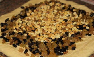 Rol het deeg uit tot een vierkant. Verdeel rozijnen en gekonfijt fruit met noten erop.