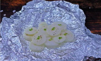 Och medan tonfisken marineras skär du löken i ringar - lägg i mitten av ett ark folie och peppar.