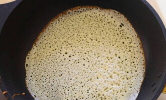 Trước khi làm chiếc bánh pancake đầu tiên, hãy bôi dầu thực vật lên chảo rán đã đun nóng. Đổ bột vào và trải đều trên toàn bộ bề mặt. Chiên cho đến khi bột có màu nâu rõ rệt xung quanh các cạnh và bong bóng xuất hiện và nổi lên trên bề mặt bánh.