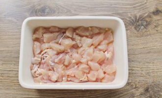 Skölj köttet och ta bort fukt med hushållspapper, skär i passande bitar. Jag har filé, men för saftighet är det tillåtet att använda lårkött Smörj en bakbehållare med vegetabilisk olja och fördela kycklingköttet. Tillsätt salt och peppar.