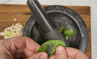 Para ihanda ang dressing, pilasin ang hinugasang dahon ng kaffir lime at ilagay sa mortar.