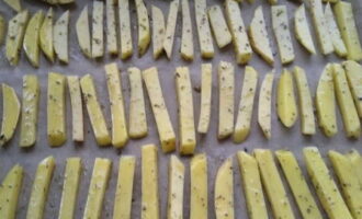Col·loqueu les patates preparades sobre paper sulfuritzat en una safata de forn.