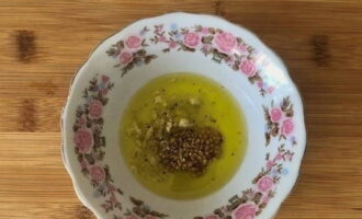 I en djup tallrik, kombinera olivolja, citronsaft, dijonsenap, hackad vitlöksklyfta, en nypa salt och mald svartpeppar. Blanda väl.