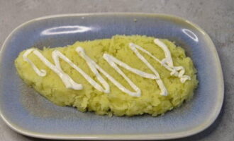 Vi formar salladen. Lägg det första lagret av förkokt, kyld och riven potatis på en platt tallrik. Lägg grönsakslagret tätt och häll majonnäs över det.