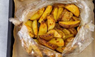 Poseu la safata de forn amb les patates al forn.En aquest moment ja s'hauria d'escalfar bé. Enfornar durant 30-40 minuts. Per obtenir una deliciosa crosta daurada, talleu la màniga i enforneu les patates descobertes durant 5-7 minuts més.