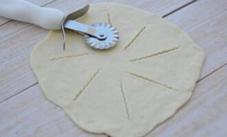 La massa restant la farem servir per decorar. Enrotlleu 15-20 grams en una bola, servirà de tapa per al forat del centre del pastís. Estireu la resta de la massa i feu diversos talls des del centre fins a la vora.