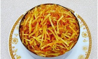 A rétegeket megszórjuk kihűlt burgonyacsíkokkal. Tálalás előtt tartsa a csemegét a hűtőszekrényben, majd távolítsa el a tálalógyűrűt.